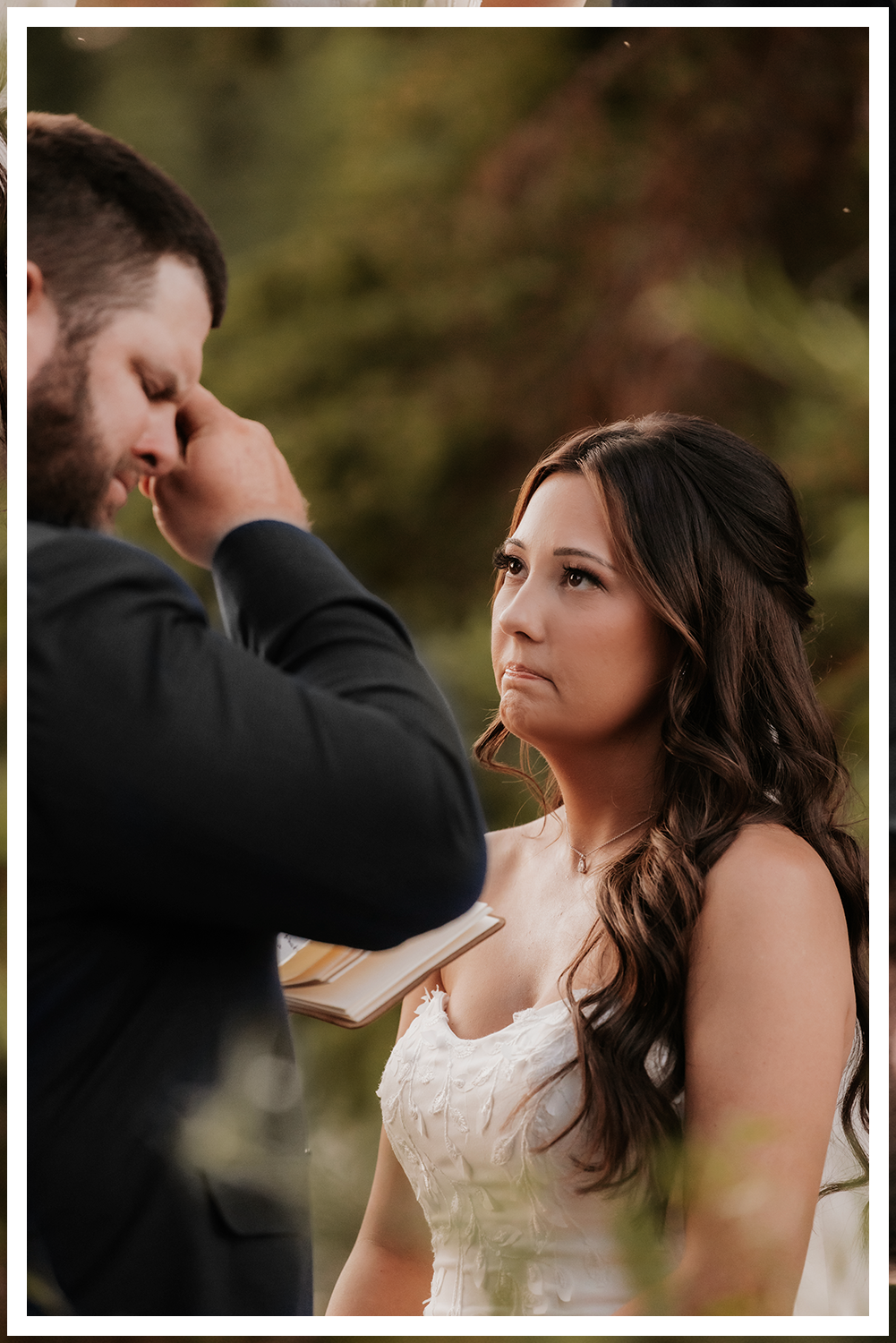 A wedding couple in Dead Horse State Park standing on a large stack of deep red stone at sunset with cinematic hazy lighting near the edge of the cliff.