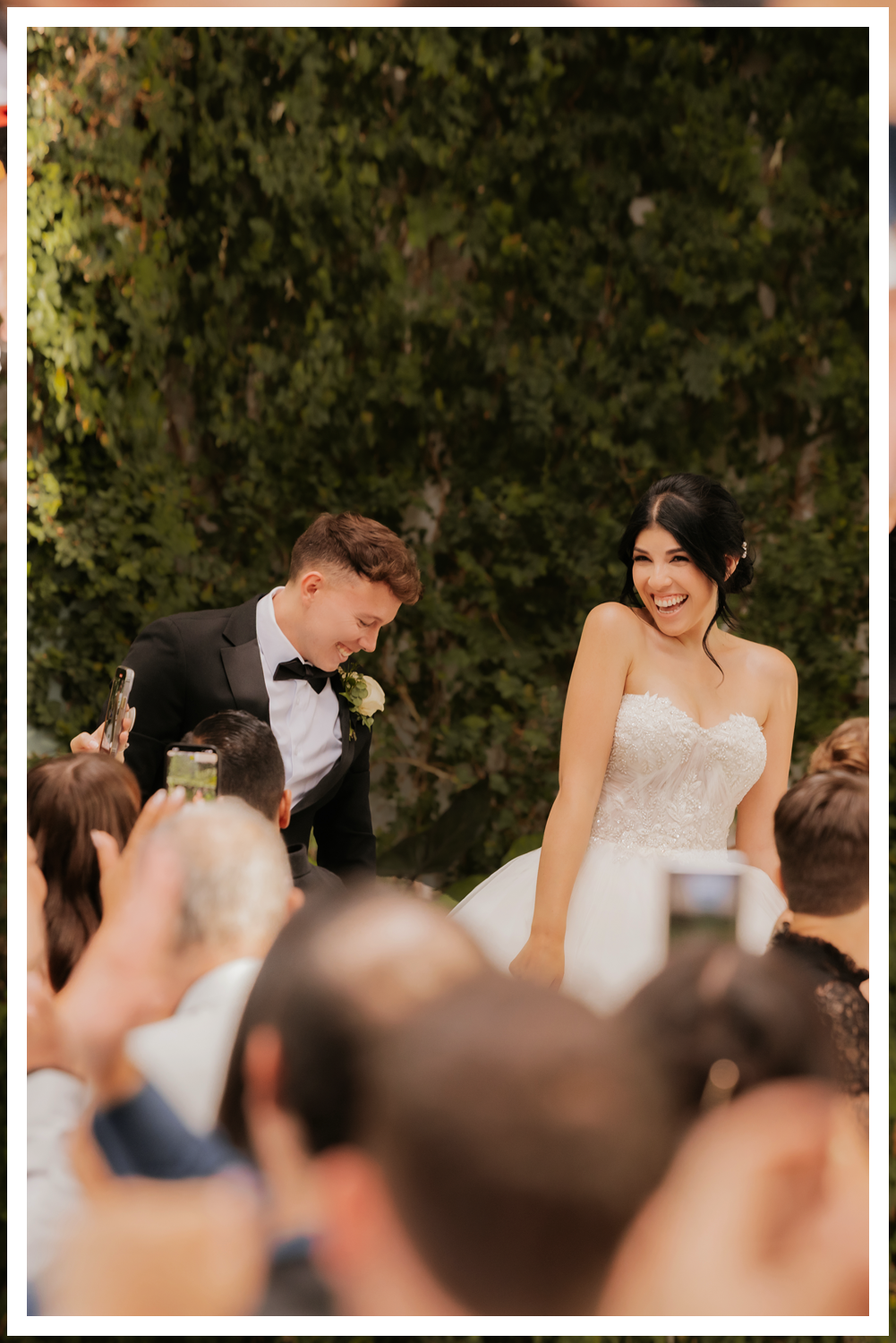 A wedding couple in Dead Horse State Park standing on a large stack of deep red stone at sunset with cinematic hazy lighting near the edge of the cliff.