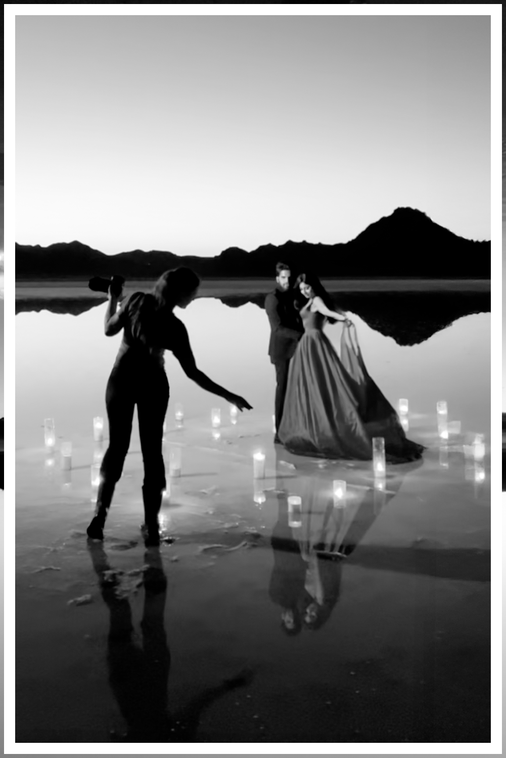 A wedding couple in Dead Horse State Park standing on a large stack of deep red stone at sunset with cinematic hazy lighting near the edge of the cliff.