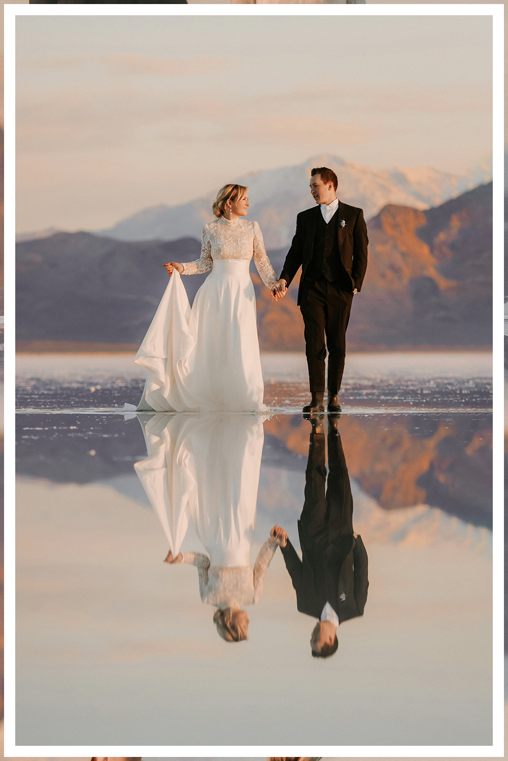 A bride and groom in ornate Indian clothing with a vast desert landscape with stormy skies and lighting with dreamy sunset lighting.